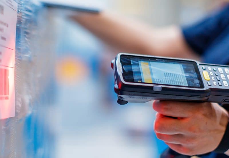 Logistikmitarbeiter scannt mit Handheld im Lager ein Barcode